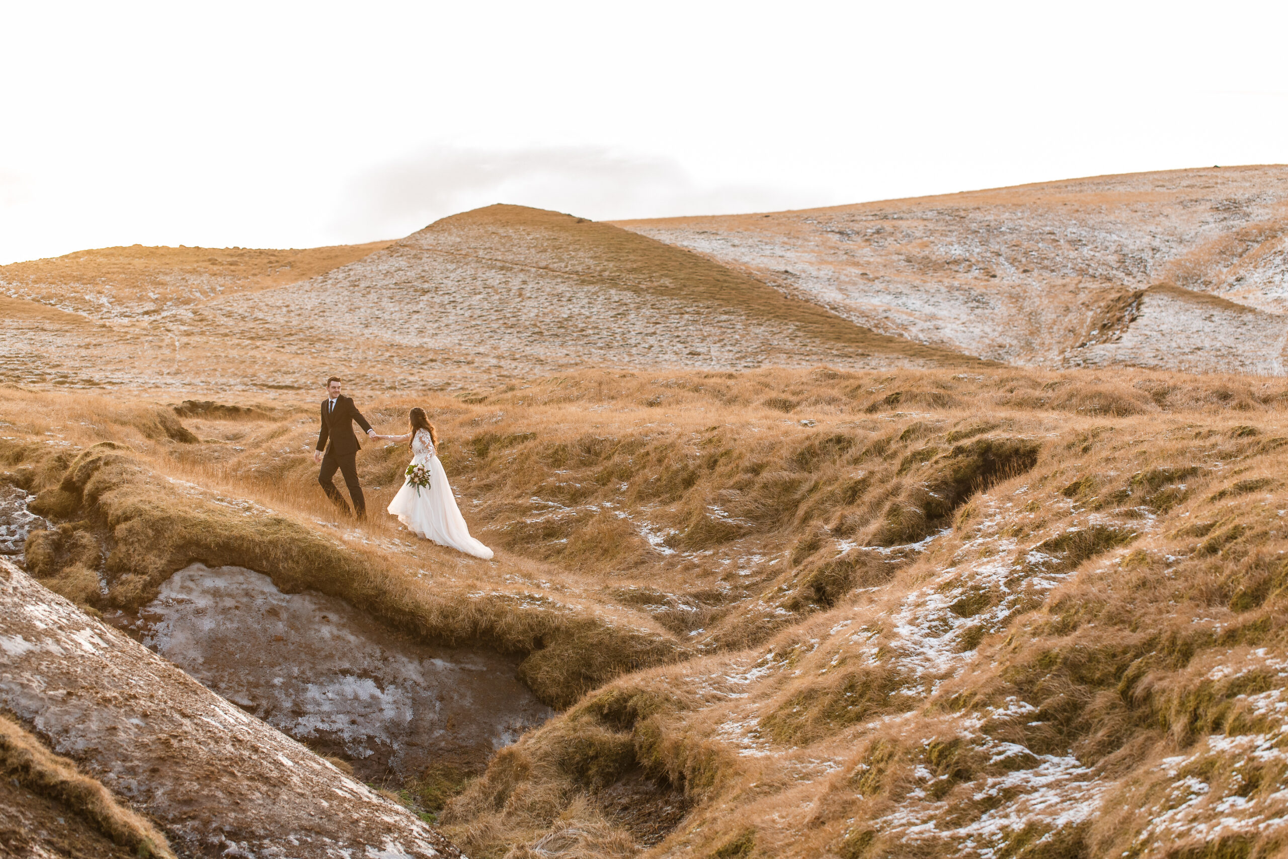a couple walking through some frozen grass in iceland 