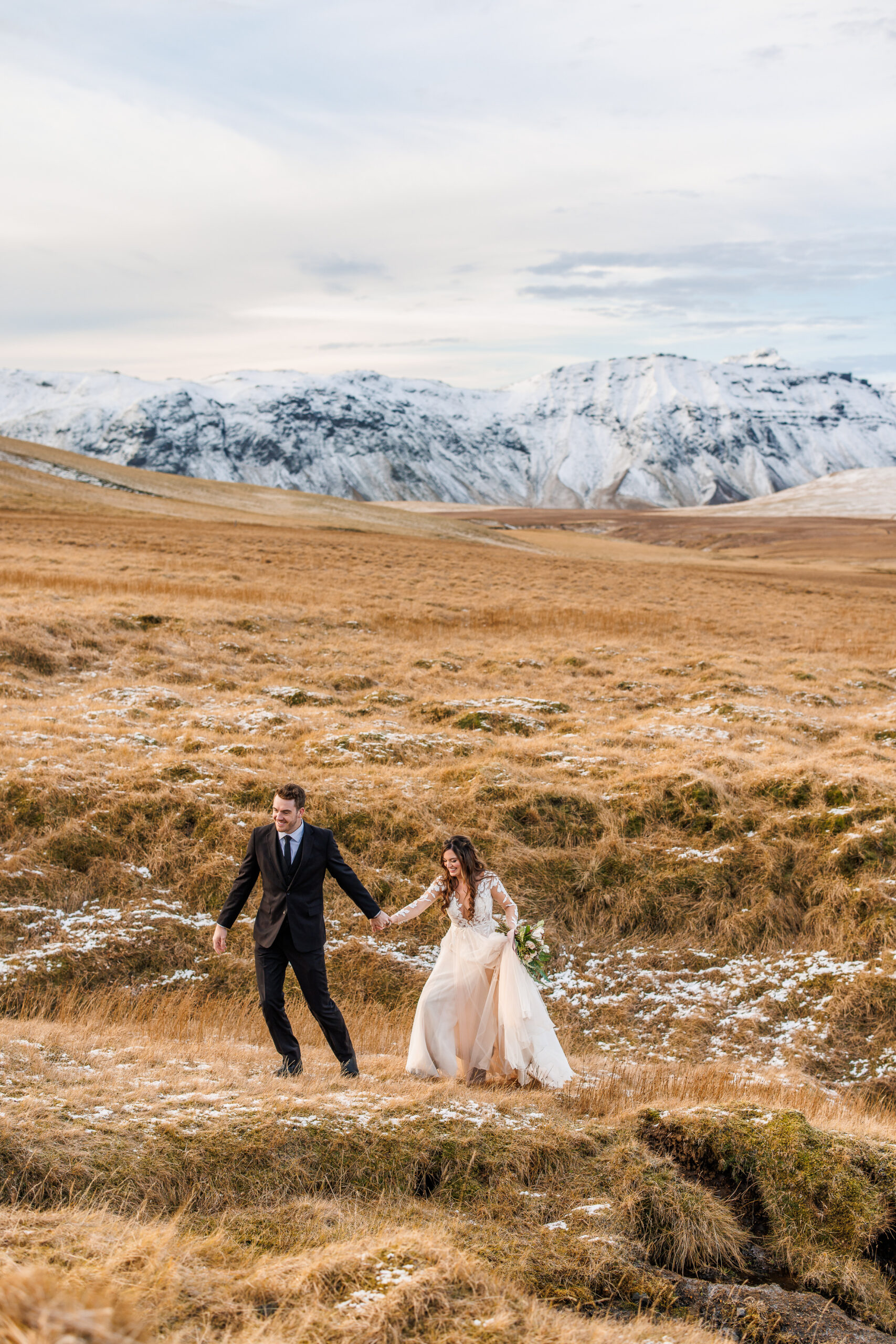 a couple walking through a grass field in Iceland 