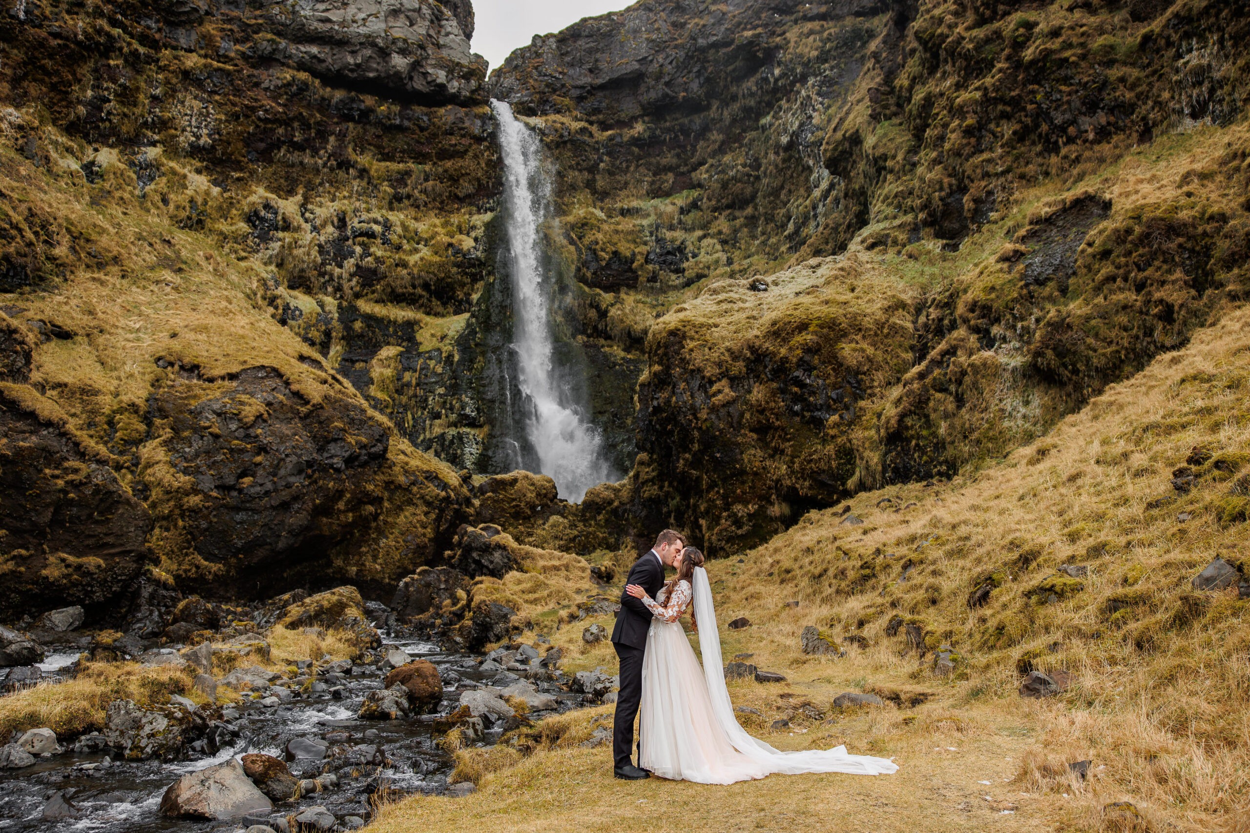 a couple kissing in front of a waterfall during their mountain elopement in Iceland 