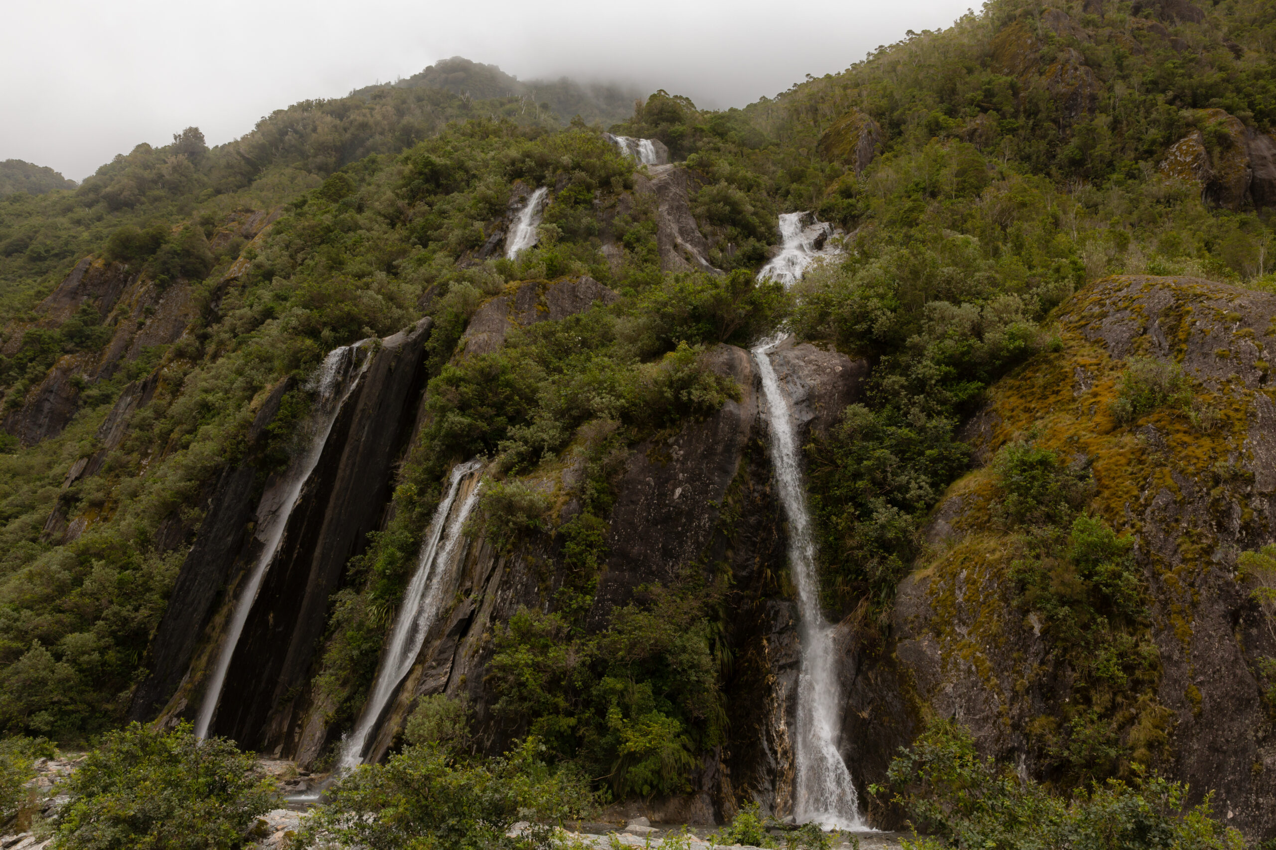 a waterfall coming down a mountain in NZ